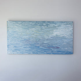 A abstract painting with blue textured brushstrokes is hung on a gallery wall.
