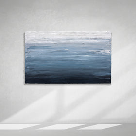 A dark navy blue, light blue, blue, and white thickly textured abstract painting hanging on a white wall in natural light by Teodora Guererra.