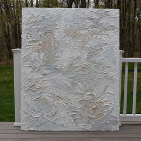 An abstract painting with thickly textured brushstrokes of beige, green, orange, and blue sitting on the artists deck.