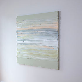 A peach, grey, white, celadon and sage green thickly textured painting side view, hanging on a white wall by Teodora Guererra.