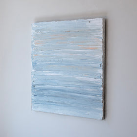 An abstract painting with thick impasto brushstrokes of blue and yellow paint is seen at an angle on a gallery wall.