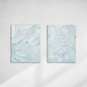 A pair of thickly painted paintings in teal, sea foam green, celadon, white and hints of siena by Teodora Guererra hang on a white wall. The two painting are like wall sculptures.