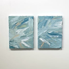 A video of a pair of thickly painted paintings in teal, sea foam green, celadon, white and hints of orange and yellow by Teodora Guererra hanging on a white wall. The two painting are like wall sculptures.