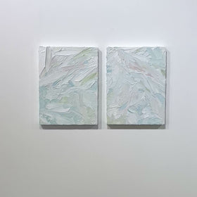 A video of a pair of thickly painted paintings in teal, sea foam green, celadon, white and hints of siena by Teodora Guererra hang on a white wall. The two painting are like wall sculptures.