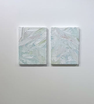 A video of a pair of thickly painted paintings in teal, sea foam green, celadon, white and hints of siena by Teodora Guererra hang on a white wall. The two painting are like wall sculptures.