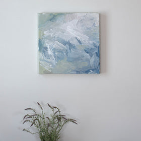 A painting is hung above a shelf. It is decorated in white, blue and green paint applied in a thick impasto to its surface. Wired and ready to hang.