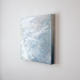 A painting is shown hanging on the wall at an angle. Its surface is decorated with white, blue and green paint in a thick impasto. Wired and ready to hang.