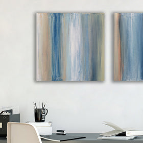 One of a pair of paintings painted with blue, white, tan and green streaks hangs above a black desk with a plant books, pencils and white chair. Wired and ready to hang.