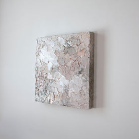 A painting is shown hanging on the wall at an angle. Its surface is decorated with white, pink and grey paint in a thick impasto. Wired and ready to hang.